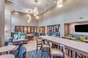 a waiting room with tables and chairs and a flat screen tv at Hampton Inn & Suites Saraland Mobile in Saraland