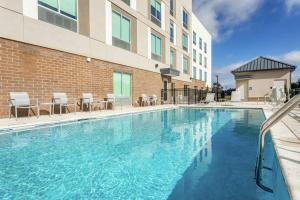 a swimming pool with chairs and a building at Hampton Inn & Suites Saraland Mobile in Saraland