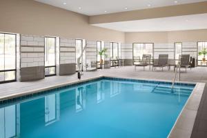 una piscina en una habitación de hotel con sillas y mesas en Hampton Inn & Suites Charlotte Steele Creek Road, NC en Charlotte
