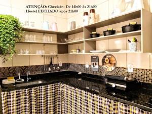 uma cozinha com um balcão de azulejos pretos e amarelos em Elô Hostel em Brasília