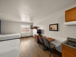 een kleine kamer met een bed en een tafel en stoelen bij WoodSpring Suites Dallas Rockwall in Rockwall