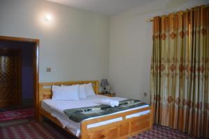 的住宿－Besham Hilton Hotel, by LMC，一间卧室配有一张木框床和窗帘