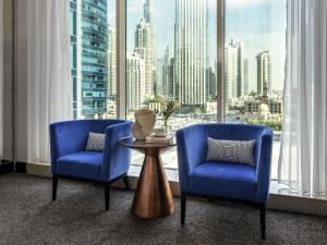 two chairs and a table in a room with a large window at Pullman Dubai Downtown in Dubai