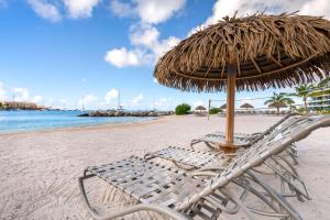 a straw umbrella and chairs on a beach at Hilton Vacation Club Royal Palm St Maarten in Simpson Bay
