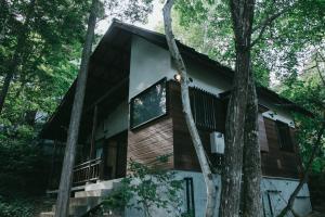 a cabin in the woods with trees at 無添加料理と天然温泉つきの ちいさな貸別荘 little villa 柊日 in Azumino