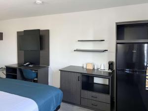 a room with a bed and a kitchen with a refrigerator at Studio 6 Suites Delano, CA in Delano