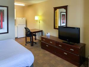 um quarto de hotel com uma cama, uma televisão e uma secretária em Studio 6 Columbus GA Columbus Airport em Columbus