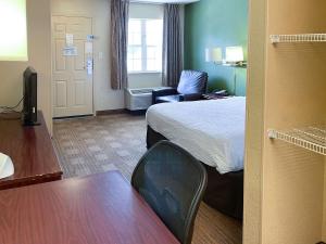um pequeno quarto de hotel com uma cama e uma cadeira em Studio 6 Columbus GA Columbus Airport em Columbus