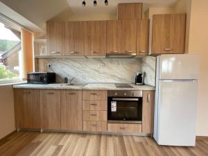 a kitchen with wooden cabinets and a white refrigerator at Hancho - Velingrad - Marvel Apartament in Velingrad