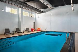 a swimming pool in a room with chairs and a table at Aloft Leawood-Overland Park in Overland Park