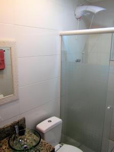 La salle de bains est pourvue de toilettes et d'une douche en verre. dans l'établissement Recanto aconchegante no Campeche Apart 05 - 50m da praia -, à Florianópolis