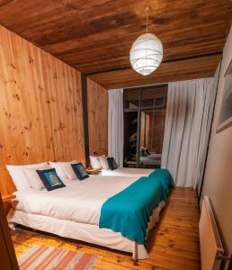 1 dormitorio con 1 cama grande y paredes de madera en Surf Lodge Punta de Lobos, en Pichilemu