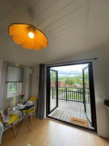 a living room with a large door to a balcony at Pwllglas Bach - Spacious Cabin in Machynlleth