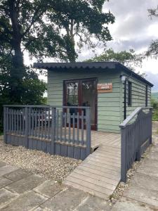 a small green building with a wooden fence at Pwllglas Bach - Spacious Cabin in Machynlleth