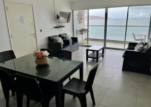 ein Wohnzimmer mit einem Tisch und Stühlen sowie Meerblick in der Unterkunft 501 Velas Primera Fila Vista Bahía Paracas 110 Metros - 501 T1 in Paracas