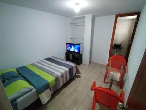 ein kleines Schlafzimmer mit einem Bett und einem TV in der Unterkunft Alojamiento SEVADA Derrama Magisterial in Chiclayo