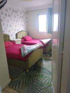 - 2 lits dans une chambre avec des draps roses et une fenêtre dans l'établissement شقه فندقيه بغرفتي نوم اول نمره من البحر كافيه البارون, à Alexandrie