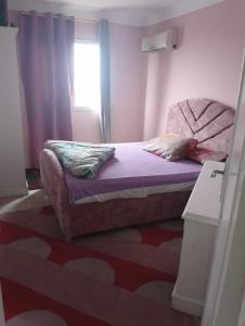 - une chambre avec un lit doté de draps violets et une fenêtre dans l'établissement شقه فندقيه بغرفتي نوم اول نمره من البحر كافيه البارون, à Alexandrie