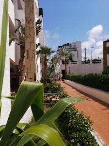 een binnenplaats met palmbomen en een gebouw bij Appartement Al cudia smir in Fnidek