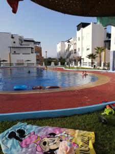 een zwembad met mensen in het water bij Appartement Al cudia smir in Fnidek