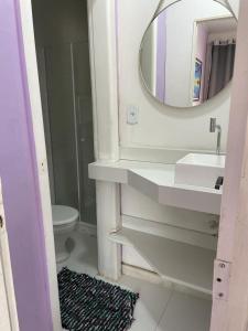 a bathroom with a sink and a mirror and a toilet at Nascimento Suites in Búzios