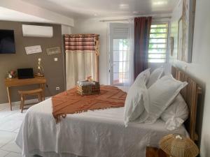 una camera da letto con letto, lenzuola e cuscini bianchi di AU PIPIRI LÉVÉ a Schœlcher