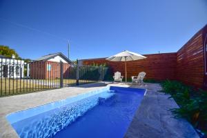 una piscina azul con sombrilla, silla y sombrilla en Macleay Cottage with plunge pool and local arts en Dubbo