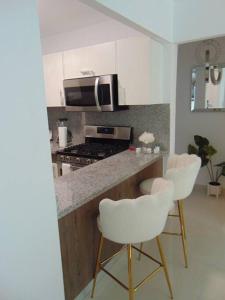 a kitchen with three white chairs and a counter top at AM.AIRBNB in Santo Domingo