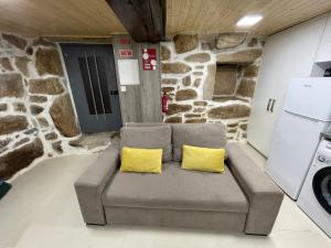 um sofá com duas almofadas amarelas num quarto com uma parede de pedra em Casa do Forno D`Aldeia em Mouços