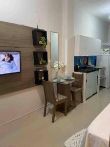 a living room with a kitchen with a tv on the wall at Apartamento encantador 6 in Montes Claros