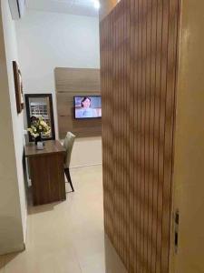 a hallway with a desk and a tv in a room at Apartamento encantador 6 in Montes Claros