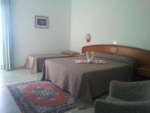 a hotel room with two beds and a chair at Hotel Eden in San Domino