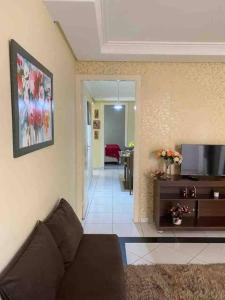 ein Wohnzimmer mit einem Sofa und einem TV in der Unterkunft Apartamento Encantador B in Montes Claros
