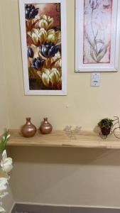 a shelf with vases on it with a painting on the wall at Apartamento encantador 04 in Montes Claros