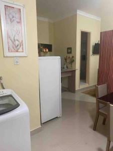 a kitchen with a white refrigerator and a table at Apartamento encantador 04 in Montes Claros