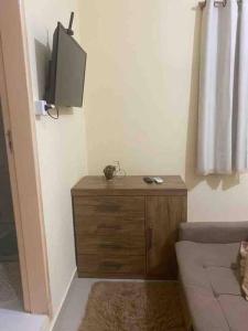 ein Wohnzimmer mit einem TV und einer Holzkommode in der Unterkunft Apartamento encantador 04 in Montes Claros