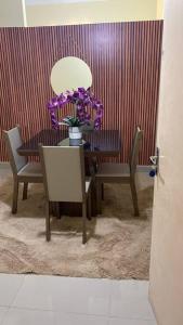 Apartamento encantador 04 في مونتيس كلاروس: غرفة طعام مع طاولة وكراسي مع زهور أرجوانية