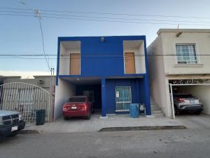 una casa azul con autos estacionados frente a ella en Hospedaje JrzConsulado en Ciudad Juárez