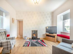 a living room with a fireplace and a tv at Lincumtoy in Ballantrae