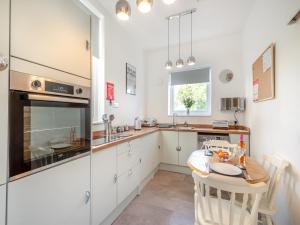 a kitchen with white cabinets and a table and a sink at Lincumtoy in Ballantrae