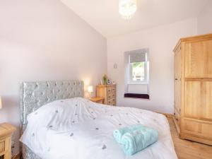 a bedroom with a white bed with a blue towel on it at Lincumtoy in Ballantrae