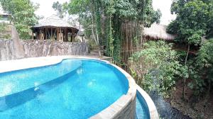 a swimming pool in a yard with a gazebo at The Osing Bamboo Resort - a LIBERTA Collection in Banyuwangi