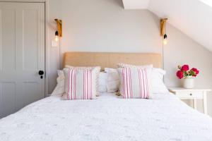 a bedroom with a white bed with pink and white pillows at Anchor Weighbridge House, Winchcombe - 4 bed, 4 bath in Winchcombe