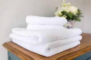 een stapel handdoeken op een tafel met een vaas met bloemen bij Anchor Weighbridge House, Winchcombe - 4 bed, 4 bath in Winchcombe