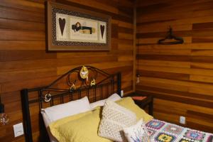 een slaapkamer met een bed in een kamer met houten wanden bij Refúgio Amor Demasiado in São Francisco de Paula