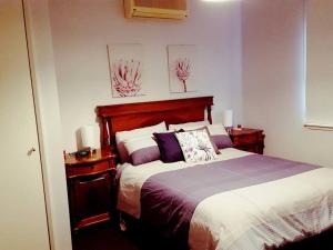 1 dormitorio con 1 cama grande y 2 mesitas de noche en Wild Brumby- A cozy home away from home, en Corryong