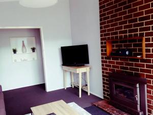 a living room with a fireplace and a television at Wild Brumby- A cozy home away from home in Corryong