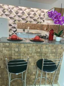 a kitchen with two chairs and a counter with plates and wine glasses at Apartamento encantador 3 in Montes Claros