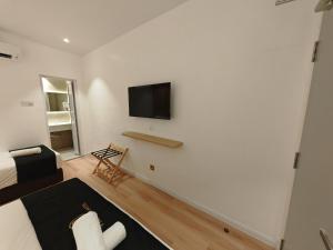 a living room with a bed and a tv on a wall at V Boutique Hotel Seremban in Seremban