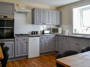 una cocina con armarios grises y electrodomésticos blancos en Montys, en Castle Douglas